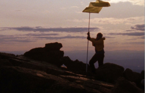 man standing on a hill with a sunset behind him