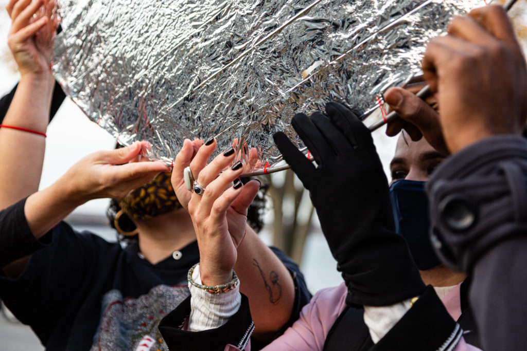 close up photo of peoples hands holding up a large silver disc