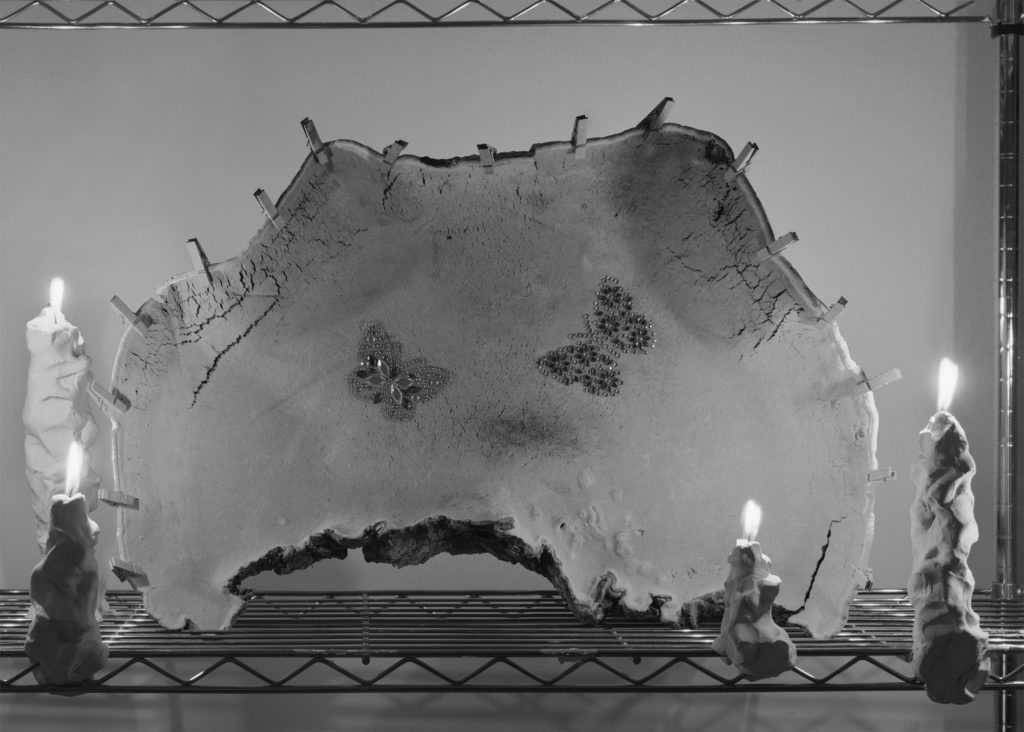 A black and white photos of a material with butterflies printed on it and candles lit.