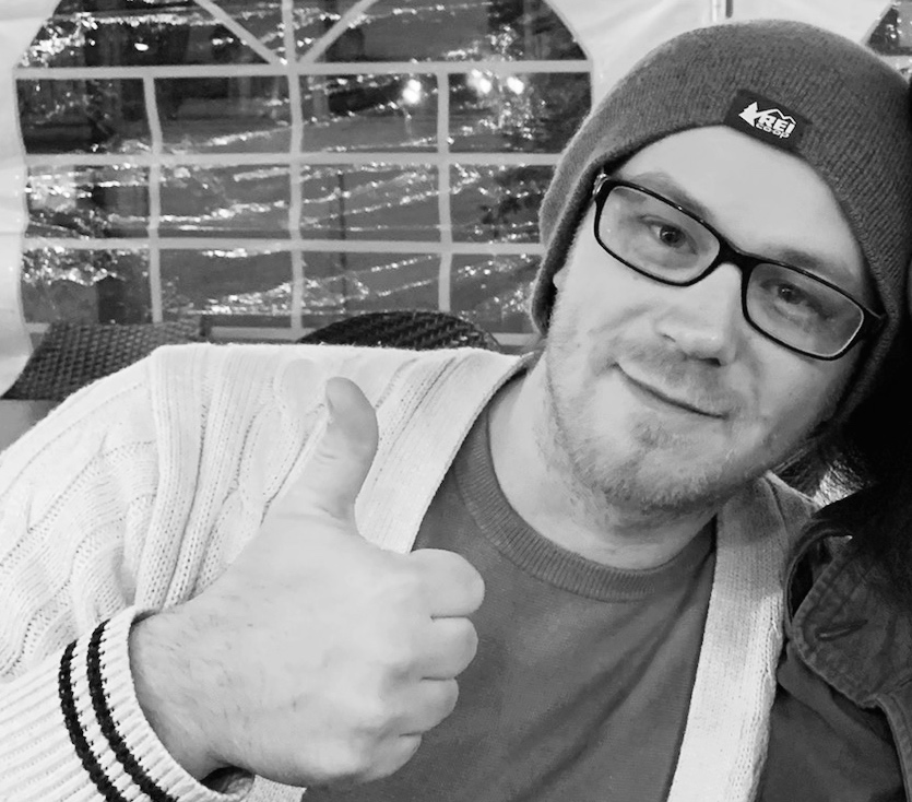 Black and white headshot of Bobby giving the thumbs up sign
