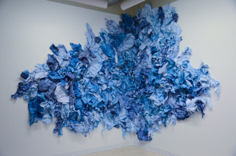 Blue sculptural artwork in corner of room on white wall