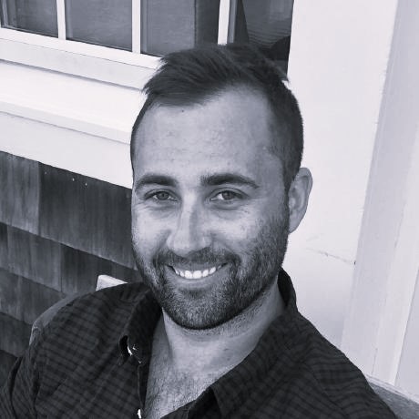 A black and white head shot of Rick Bresnahan smiling, with a beard.