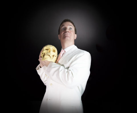 a man in a white suit holding a skull