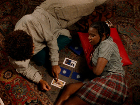 two people sitting on a rug pointing at cards