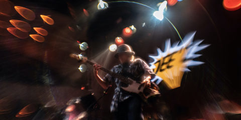 A hazy image of a young rock and roller on stage in bleary lights looking impossibly cool.