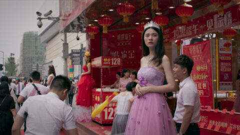 a woman in a pink dress standing on a street