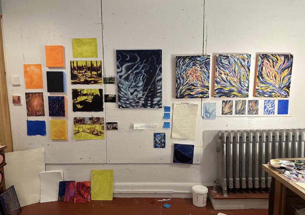 The SPACE residency studio wall covered in colorful watercolor works and paintings by Raquel Miller with a radiator and work desk in the corner.