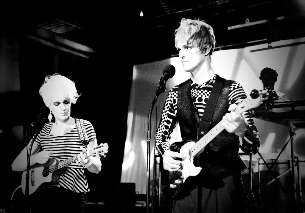A black and white photograph of CVK performing on a stage with big hair and eyeliner. Photo by Erin X. Smithers.