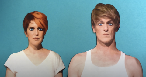 A still from a stop motion animation of the two members of CVK in white shirts as paper cutouts against a blue background with painted on eyes.