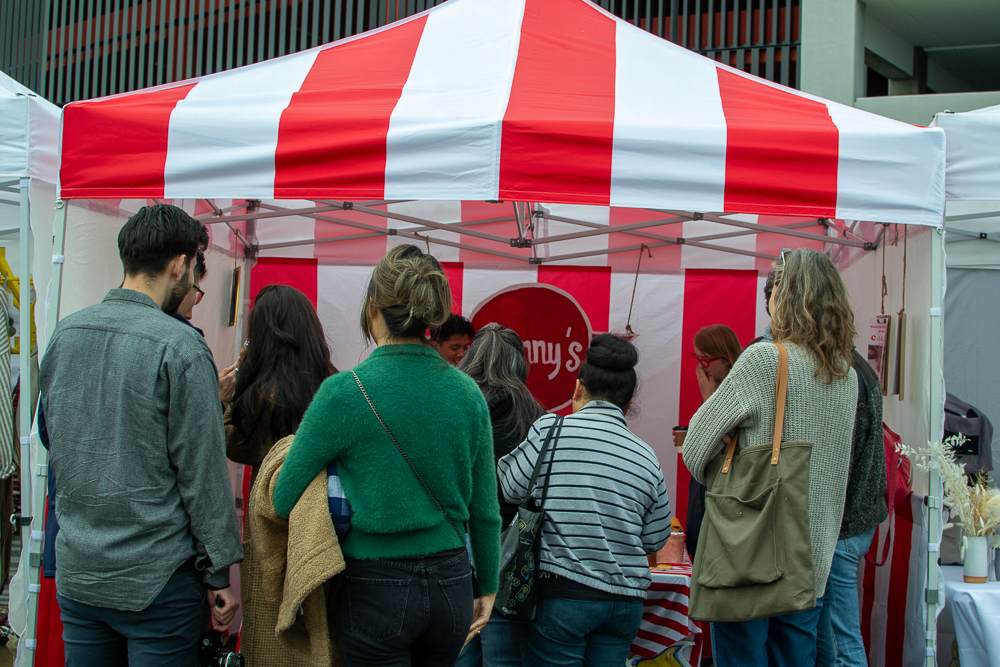 crowd of people approaching a red and white striped vendor stand