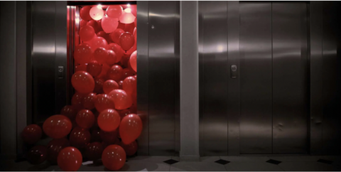 An image mimicking the famous shot of the film The Shining where blood comes out of an elevator, but instead red balloons are pouring out of the elevator.