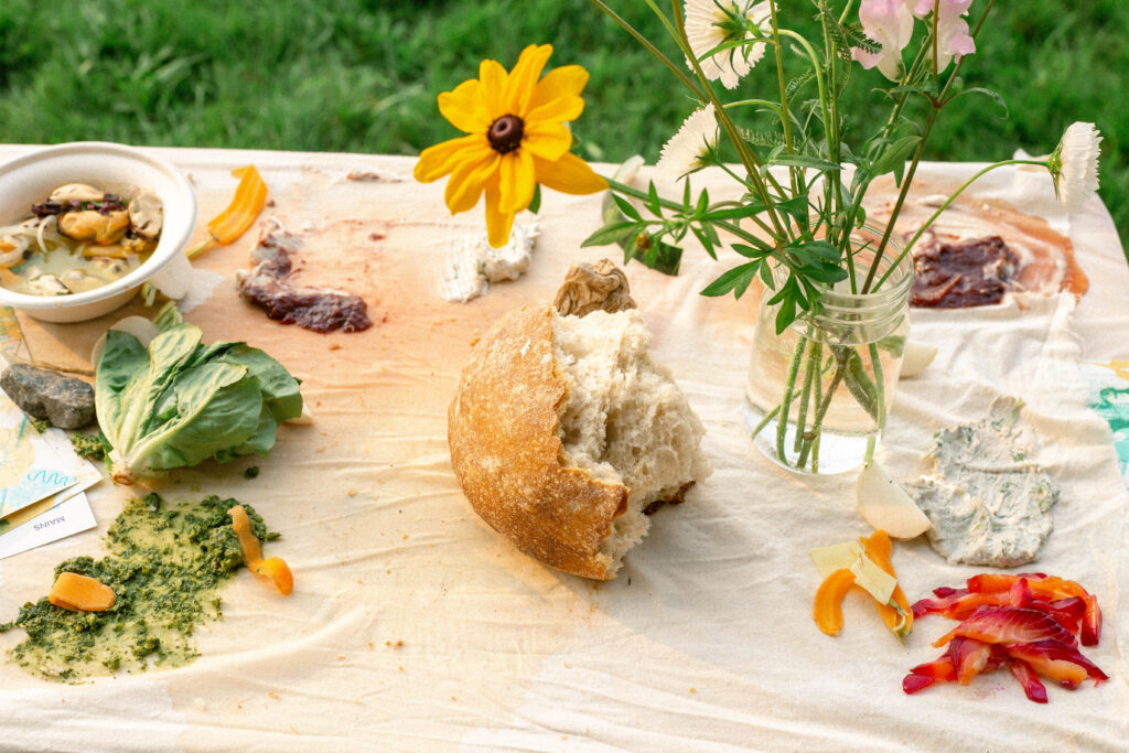 a torn piece of bread sits on a colorful table adorned with flowers and finger foods
