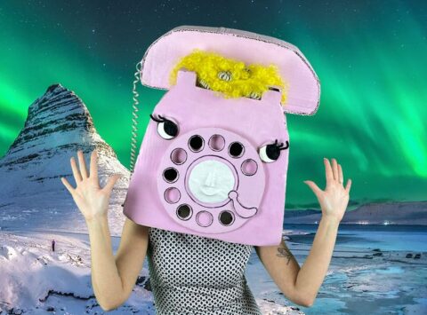 A person wearing a pink rotary telephone costume against an image of the Northern Lights.