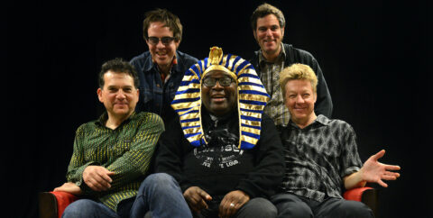 Barrence Whitfield and the Savages sitting together, smiling. Barrence is wearing a full Egyptian Pharaoh headdress. He looks great.