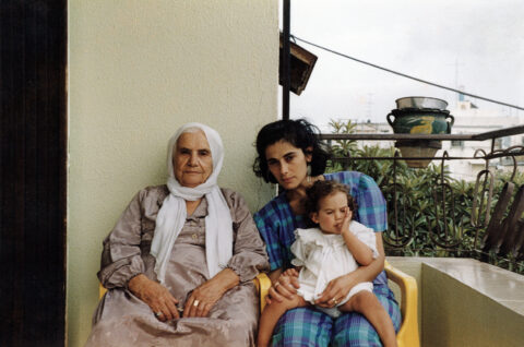 A still from the film featuring three women from different generations sitting on a porch outside.