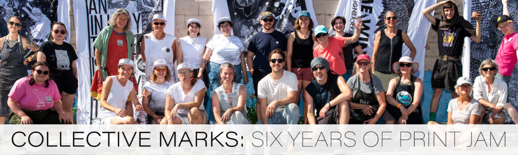 A banner style image with two rows of artists smiling at the camera with large scale black ink on white sheet prints from the Print Jam hanging behind them.