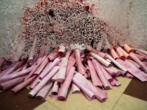 The artist's work, titled Everything I Never Told My Mother consists of laser cut rice paper hanging over dozens of pink natural dyed rice paper scrolls