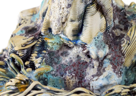 An abstract detail of one of Jackie Brown's ceramics works, looking like layered strata with abstract multi-colored glazes on top.